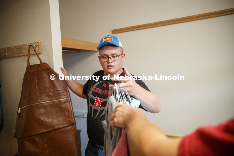 Tristan Smith, from Curtis, Nebraska, grabs a handful of clothes to hang. Massengale Residential Center move in. August 21, 2019. Photo by Craig Chandler / University Communication.