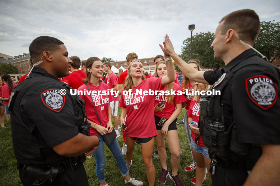 Officer Craig Tepley high-fives Lauren Lintner of Chicago after he explained why the game Corn Hole is called that in Nebraska. Officers Terrell Long Jr. and Craig Tepley were challenged to a game by Hebron students McKenzie Johnson and Emily Welch. The Hebron duo won. Big Red Welcome, Chancellor's BBQ for incoming freshman and new students on the greenspace by the Memorial Union. August 23, 2019. Photo by Craig Chandler / University Communication.