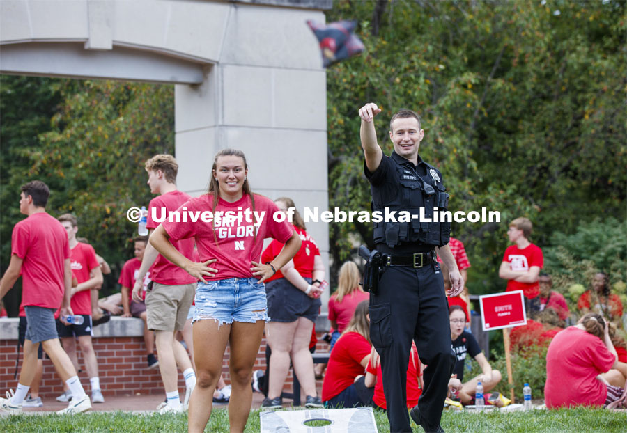 UNL Police Officer Craig Tepley shows his corn hole form at the picnic. He and fellow officer Terrell Long Jr. were challenged to a game by Hebron students Emily Welch, at left, and McKenzie Johnson. The Hebron duo won. Big Red Welcome, Chancellor's BBQ for incoming freshman and new students on the greenspace by the Memorial Union. August 23, 2019. Photo by Craig Chandler / University Communication.