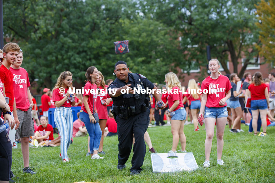 UNL Police Officer Terrell Long Jr. shows his corn hole form at the picnic. He and fellow officer Craig Tepley were challenged to a game by Hebron students McKenzie Johnson, at right, and Emily Welch. The Hebron duo won. Big Red Welcome, Chancellor's BBQ for incoming freshman and new students on the greenspace by the Memorial Union. August 23, 2019. Photo by Craig Chandler / University Communication.