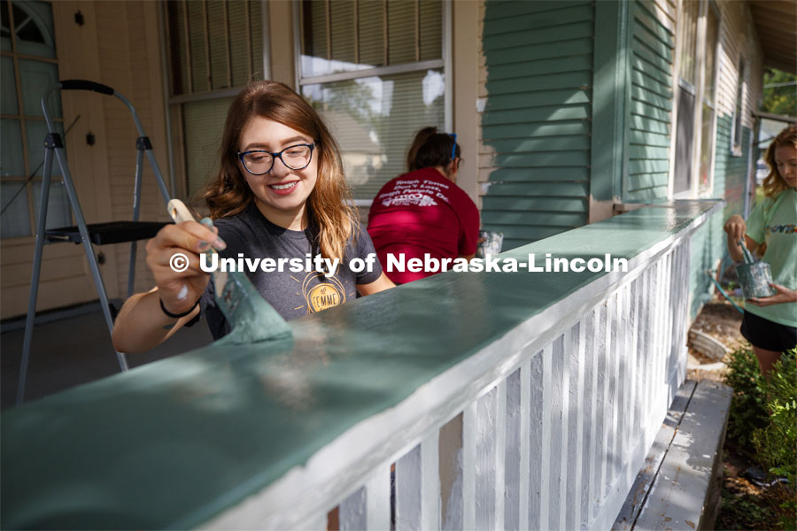 Deena Keilany of Omaha paints the porch rail of a home at 30th and Vine. First year law students, faculty and staff paint two Lincoln houses. The painting is a yearly tradition for the incoming students. August 24, 2019. Photo by Craig Chandler / University Communication.