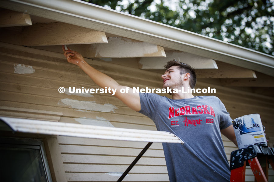 Matt Karnes of Hastings primes under the eaves of a house at 30th and Vine. First year law students, faculty and staff paint two Lincoln houses. The painting is a yearly tradition for the incoming students. August 24, 2019. Photo by Craig Chandler / University Communication.
