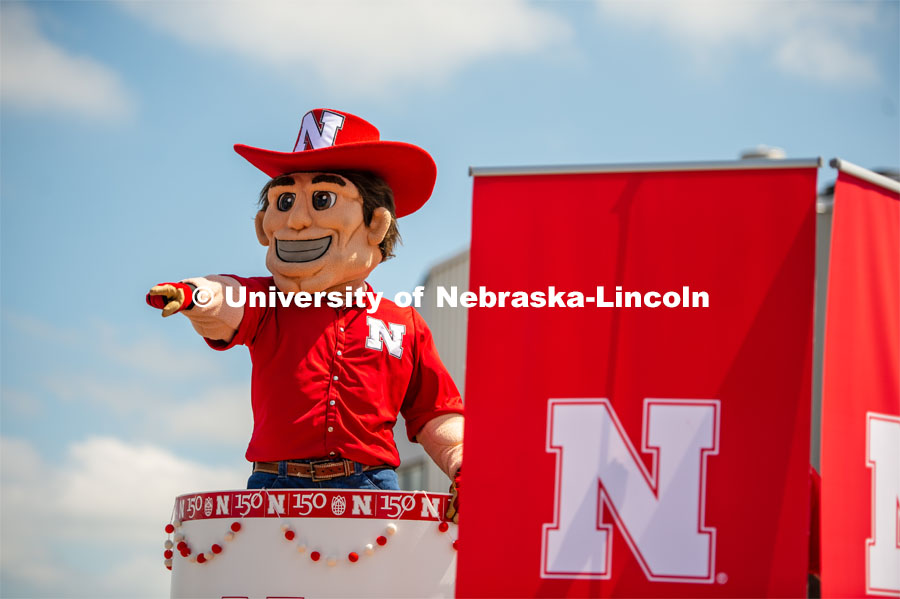 Herbie in a cake on a trailer pointing and waving to children. The University of Nebraska represents and celebrates their 150th year anniversary at the Nebraska State Fair in Grand Island, Nebraska. August 1, 2019. Photo by Justin Mohling for University Communication.