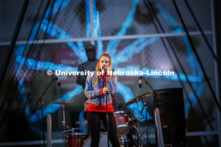 Hannah Huston, from the tv show The Voice, sings to the crowd. Behind her is the statue of Bob Devaney and the reflection of the Ferris wheel. Cornstock celebration and Homecoming Parade. October 4, 2019. Photo by Craig Chandler / University Communication.