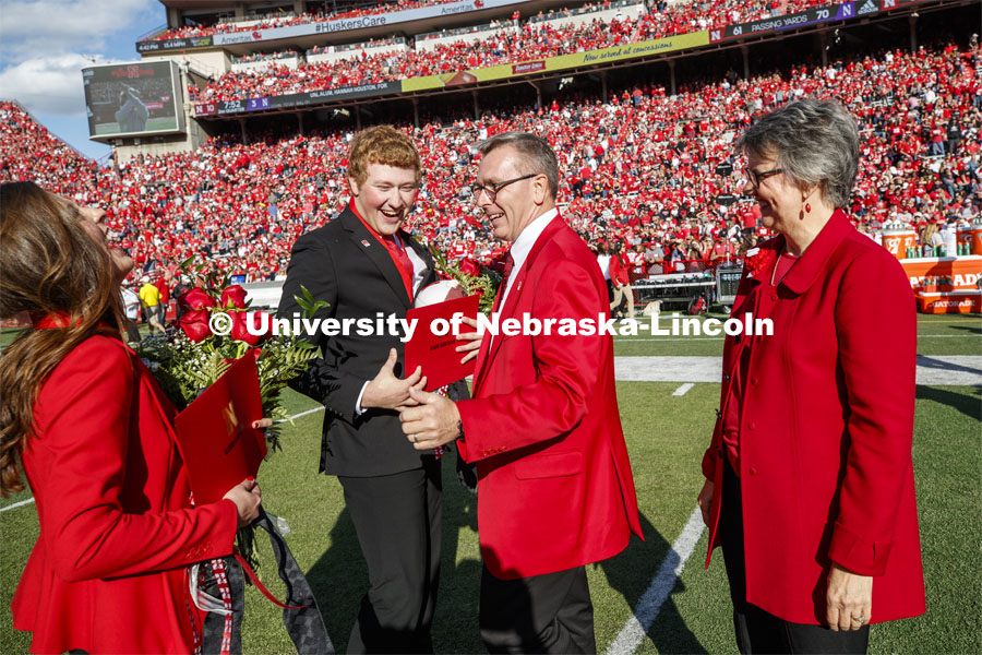 Seniors Cheyenne Gerlach and Bryce Lammers laugh with Chancellor Ronnie Green and Jane, his wife, after the halftime ceremony of the Nebraska-Northwestern football game. Nebraska vs. Northwestern University football game. Homecoming 2019. October 5, 2019.  Photo by Craig Chandler / University Communication.