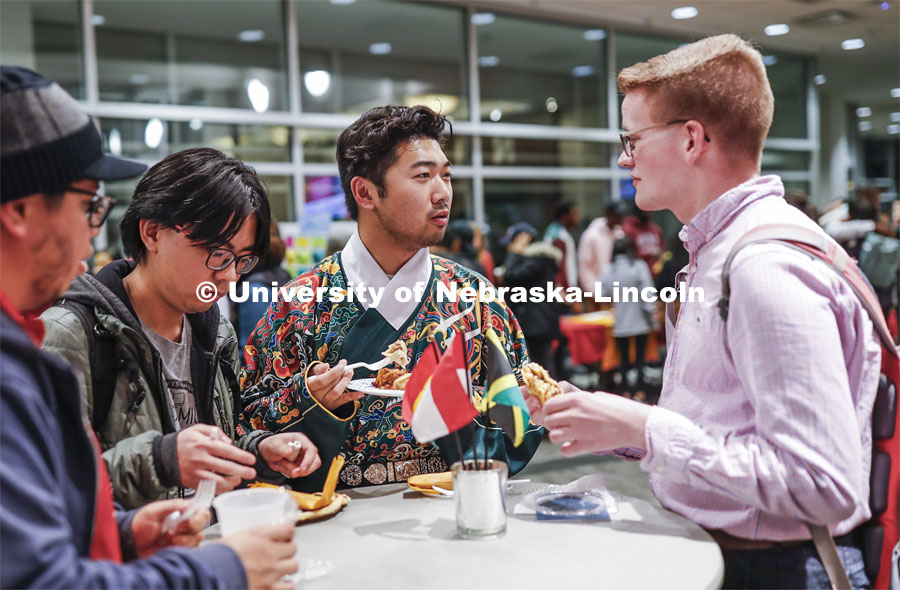 William Yao, center, talks with Andrew Neill as they sample food at the festival. Yao is wearing the undergarment for a Chinese Ming Dynasty court clothing. Global Huskers Festival, a multicultural festival provides attendees the chance to explore the world through informational booths that will have food, cultural décor, art, and more, each hosted by UNL students from those culture. November 19, 2019. Photo by Craig Chandler / University Communication.