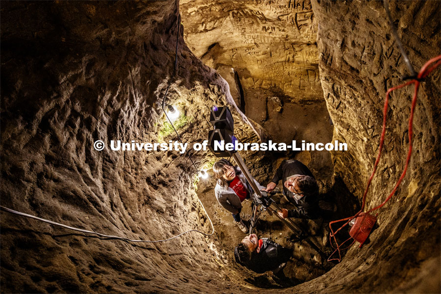 From upper left: Yijun Liao, Professor Ricky Wood and Dylan Downes raise a LIDAR unit to produce a 3-D map of the inside of Robbers Cave and the names etched into the walls. The local sandstone cave has spun legends from use by native Americans, Jesse James and the Underground Railroad to being Lincoln's first brewery.  Over the years, thousands of people has etched their names into its walls. Wood is an expert in using LIDAR to map buildings destroyed by natural disasters and was approached by the state historical society to map the cave since the soft sandstone is slowly degrading. LIDAR, which stands for Light Detection and Ranging, is a remote sensing method that uses light in the form of a pulsed laser to measure ranges. Professor Ricky Wood uses LIDAR to digitally map Robbers Cave in Lincoln. November 22, 2019. Photo by Craig Chandler / University Communication.