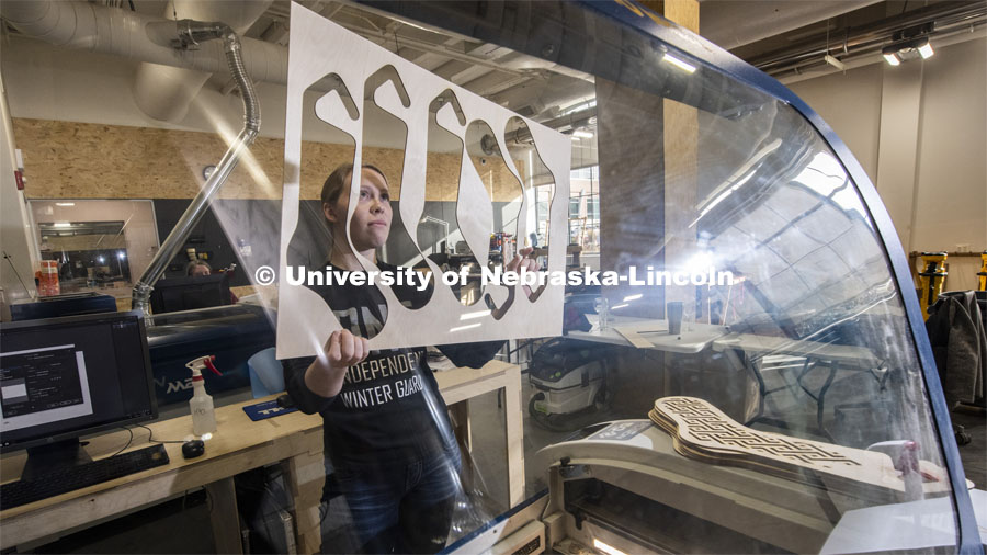 Carly Brotherson pulls sock blocks from the laser cutter at Nebraska Innovation Studio Nov. 25. Brotherson made the sock blocks for a yarn store, which requested the project through the new 'Request a Maker' button, which matches makers to projects. November 25, 2019. Photo by Greg Nathan / University Communication.