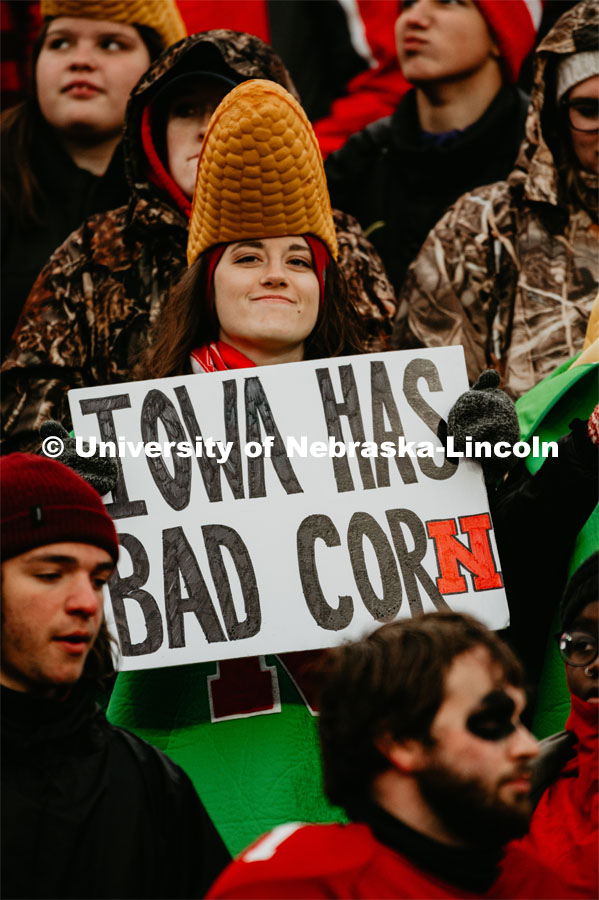 A Nebraska student decked out in her corn hat holds a sign saying Iowa has bad corn. Nebraska vs. Iowa State University football game. November 29, 2019. Photo by Justin Mohling / University Communication.