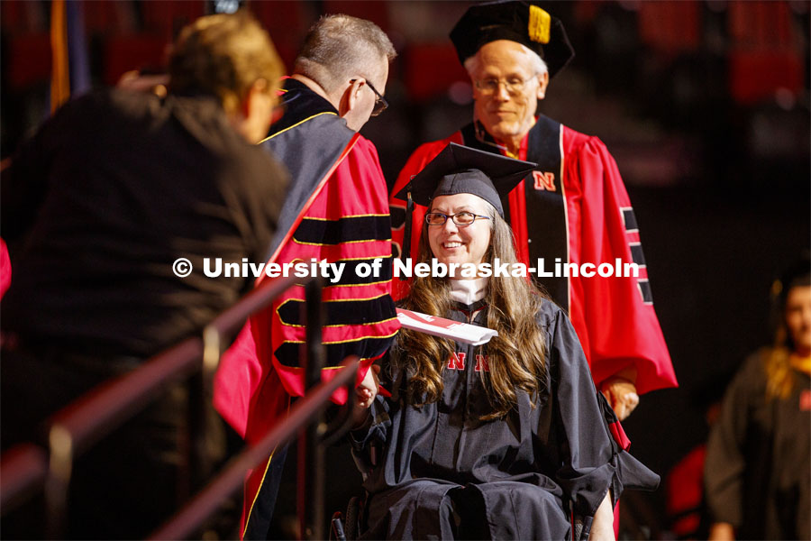 A young woman receives her diploma from Chancellor Ronnie Green. Graduate Commencement and Hooding at the Pinnacle Bank Arena. December 20, 2019. Photo by Craig Chandler / University Communication.