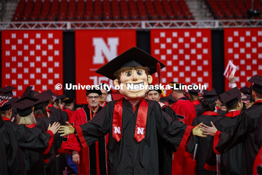Herbie Husker, decked out in his graduation cap and gown, high fives graduates as they leave the arena. December Undergraduate commencement at Pinnacle Bank Arena. December 21, 2019. Photo by Craig Chandler / University Communication.