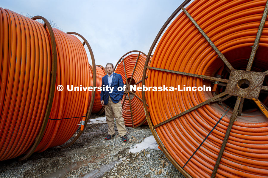 Gus Hurwitz, Nebraska Law professor researching rural broadband issues in Nebraska. Behind him are coils of conduit used to bury fiber cable. January 31, 2020. Photo by Craig Chandler / University Communication
