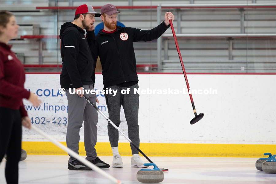 Colin Wooldrik in the purple cap and Adam Schlichtmann in the red and gray cap discuss their next throw. Nebraska's nationally-ranked curling club host its first bonspiel at the John Breslow Ice Hockey Center this weekend. The bonspiel — or tournament — featured seven traveling schools from across the Midwest. February 1, 2020. Photo by Gregory Nathan / University Communication.