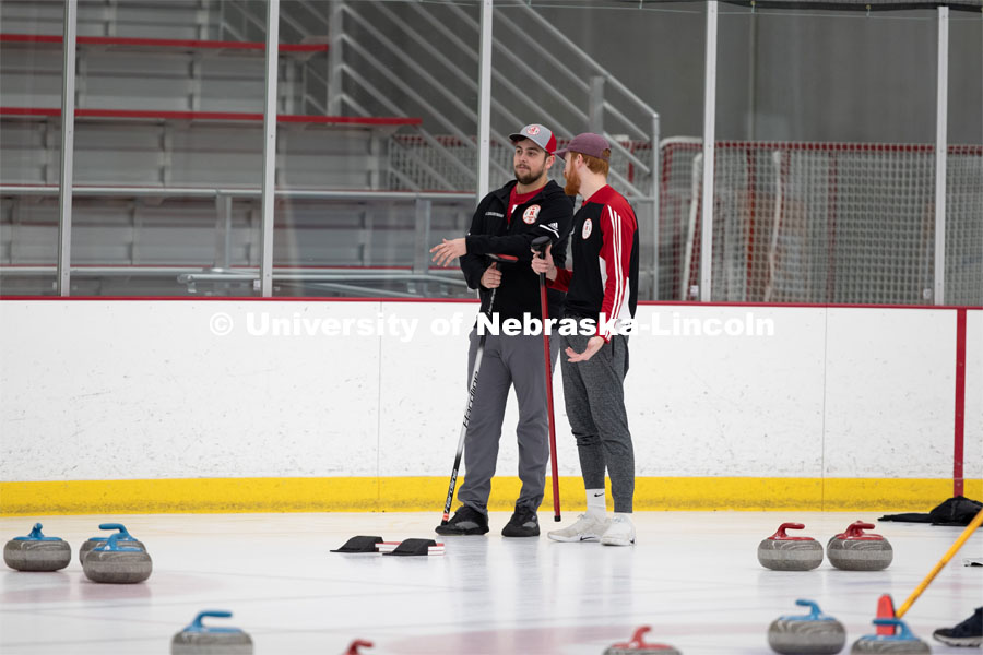 Colin Wooldrik in the purple cap and Adam Schlichtmann in the red and gray cap discuss options for their next throw. Nebraska's nationally-ranked curling club host its first bonspiel at the John Breslow Ice Hockey Center this weekend. The bonspiel — or tournament — featured seven traveling schools from across the Midwest. February 1, 2020. Photo by Gregory Nathan / University Communication.