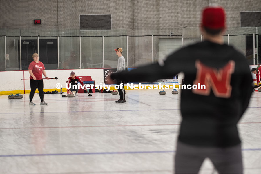 Adam Schlichtmann in the foreground gives instruction to Colin Wooldrik who is about to throw his stone, Anna Fiala and Jordan Monk prepair to sweep. Nebraska's nationally-ranked curling club host its first bonspiel at the John Breslow Ice Hockey Center this weekend. The bonspiel — or tournament — featured seven traveling schools from across the Midwest. February 1, 2020. Photo by Gregory Nathan / University Communication.