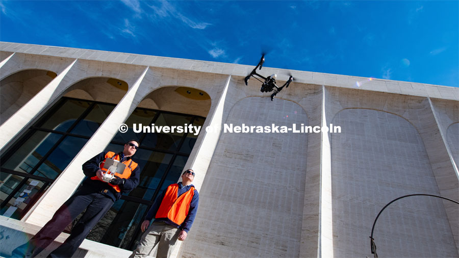 Berry Scott (from left) and Matt Raiter fly a drone outside Sheldon Museum of Art. The drones are used by the university's facilities team to identify potential damage on academic buildings. This flight is to find where the material found in the Sheldon parking lot is coming from. February 18, 2020. Photo by Gregory Nathan / University Communication.