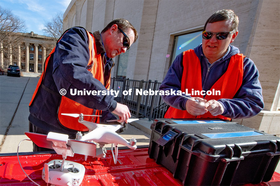 Berry Scott (from left) and Matt Raiter assemble a drone outside Sheldon Museum of Art. This flight is to find where the material found in the Sheldon parking lot is coming from. February 18, 2020. Photo by Gregory Nathan / University Communication.