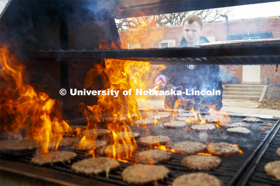 Dan Serdar, junior in Animal Science from Spring Grove, Illinois, flips hamburgers being grilled outside the Animal Science building. Lunch In The Lobby in the Animal Science building lobby is part of CASNR week. March 11, 2020. Photo by Craig Chandler / University Communication.