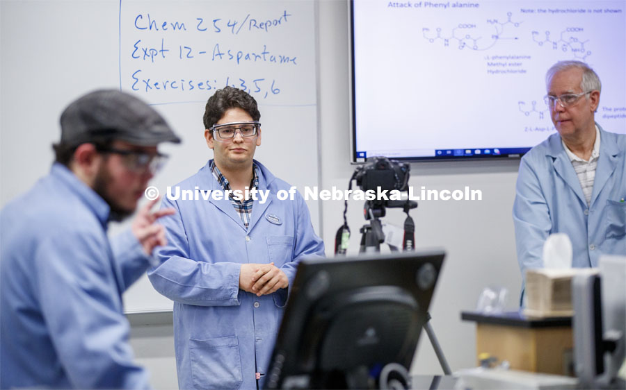 Saman Bagheri watches as Elijah Stowe counts down to the start of his recorded lab talk as he and Richard Hartung, right, record an organic chemistry lab. As a result of the Corona virus, Faculty are recording Chemistry labs in Hamilton Hall to prepare for the start of remote learning. March 24, 2020. Photo by Craig Chandler / University Communication.