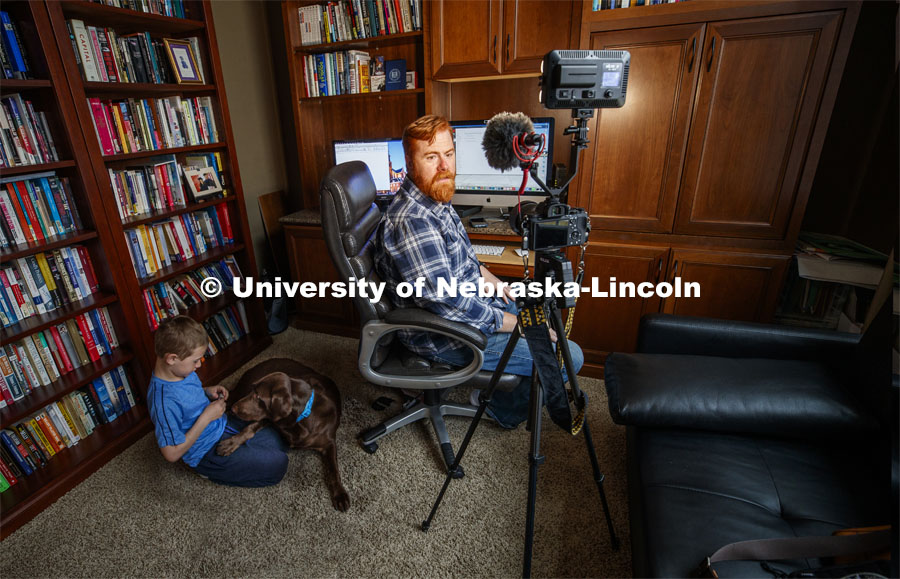 Tyler White records a lecture in his home office while his son, Gavin, 7, plays with their dog Ripley. White, Associate Professor of Practice, Political Science, was recording the lecture for his course, National Security Studies 475 - Threats and Solutions to Global Security in the 21st Century. Tyler is teaching remotely from home due to the COVID-19 virus impact on campus. March 26, 2020. Photo by Craig Chandler / University Communication.