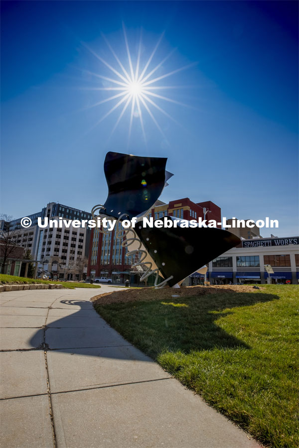 The sun shines in the blue sky above the Torn Notebook sculpture on city campus. March 30, 2020. Photo by Craig Chandler / University Communication.