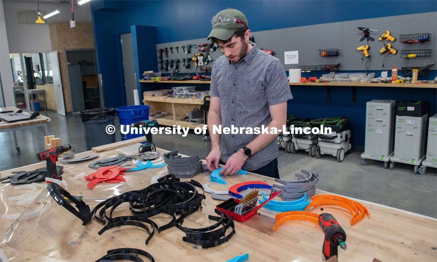 Max Wheeler, Shop Instructional Technician at Nebraska Innovation Studio, assembles face shields with parts made at NIC. Face shields have been assembled from 3-D printed and laser-cut parts, and now, injection molding will be used to mass-produce parts for face shields. The face shields are being assembled for hospitals in Nebraska in response to COVID-19. April 1, 2020. Photo by Gregory Nathan / University Communication.