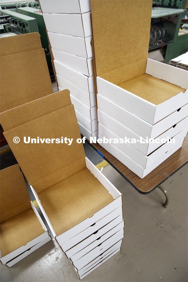 Printing Service employees work to fill the Go Big Grad boxes. Graduates will receive a "Go Big Grad" box before May 9. The box will include a complimentary mortarboard or tam, along with other surprises. April 24, 2020. Photo by Craig Chandler / University Communication.