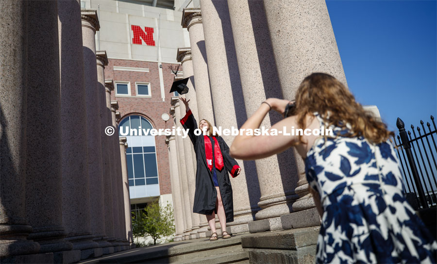 Rose Wehrman, senior in English, from Kenesaw, NE, is photographed by Sarah Schilling, senior in marketing from Omaha. The two borrowed a cap and gown (from a friend who graduated last year) to take photos of each other on campus Thursday morning. April 30, 2020. Photo by Craig Chandler / University Communication.