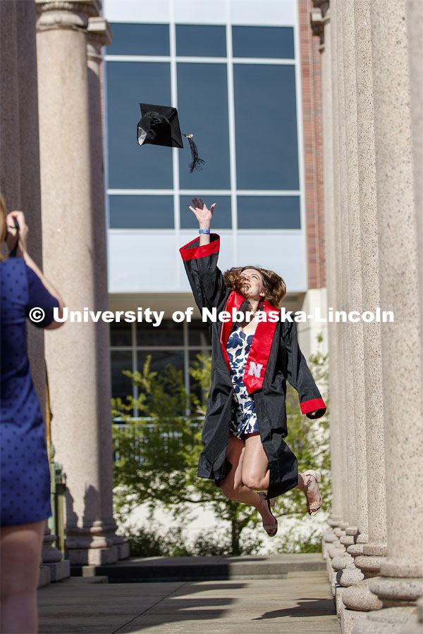Sarah Schilling, senior in marketing from Omaha, is photographed by Rose Wehrman, senior in English, from Kenesaw, NE. The two borrowed a cap and gown (from a friend who graduated last year) to take photos of each other on campus Thursday morning. April 30, 2020. Photo by Craig Chandler / University Communication.