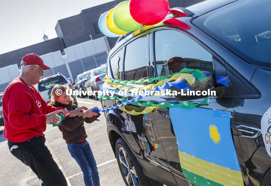 Ratch O'Connell and his granddaughter, Elisa Peters, decorate their vehicle before the parade. Blue, yellow and green balloons and streamers, the national colors of Rwanda, along with Husker Red decorated many of the vehicles. Christ Place Church families gave the Rwandan students a vehicle parade to help celebrate the graduates and undergraduates. The church has been host families for about 25 of the 50 Rwandan students who are graduating. They also provided fall and spring event off-campus marking the beginning and ending of each school year along with rides from campus to church and back each Sunday. The group of host families had been planning a graduation party for the students until COVID-19 occurred. Because of COVID-19, the group has planned for a socially distanced “parade” of host family vehicles that circled University Suites on R Street. May 8, 2020. Photo by Craig Chandler / University Communication.
