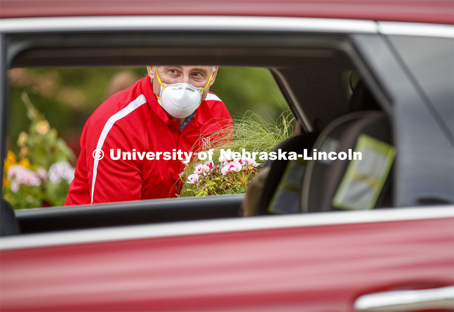 Stacy Adams, Associate Professor of Practice for Agronomy and Horticulture, waits for a driver to unlock the rear hatch so he can set a flat of flowers in the SUV. The University of Nebraska-Lincoln Horticulture Club hosted its first-ever plant giveaway Thursday, a replacement for the club's annual plant sale and fundraiser was due to the university shutdown in response to the global pandemic in mid-March. A prepackaged assortment of plants in a cardboard flat will be ready for each recipient. There were two sessions of giveaways with 100 flats of plants at each one. It only took 22 minutes to give away the morning allocation of flats. May 21, 2020. Photo by Craig Chandler / University Communication.