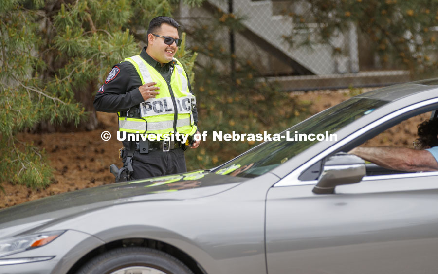 UNL Police Officer Anderson Delgado directs the huge traffic flow for people coming for the free flat of flowers left from the Horticulture Club Plant Sale. May 21, 2020. Photo by Craig Chandler / University Communication.