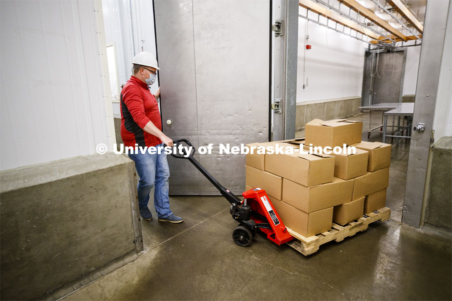 Gary Sullivan, Associate Professor in Animal Science, pulls a pallet load of processed pork toward the awaiting Lincoln Food Bank truck. UNL's Loeffel Meat Laboratory in partnership with the Nebraska Pork Producers Association Pork Cares program has donated more than 1300 pounds of processed pork to the Lincoln Food Bank. The pigs were donated by Niewohner Brothers of Albion, NE, and the pigs were harvested and processed at the east campus meat lab. May 26, 2020. Photo by Craig Chandler / University Communication.