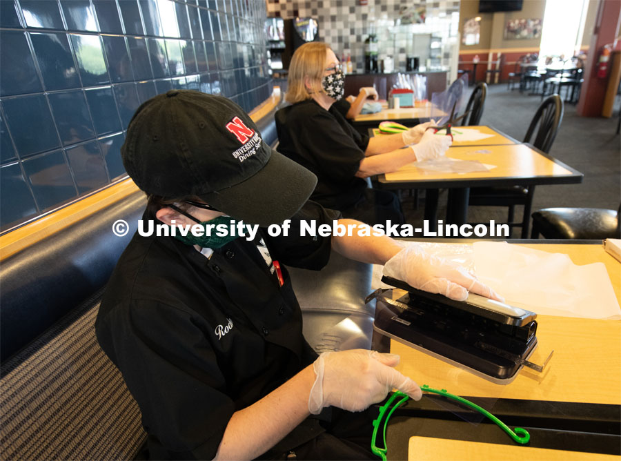 Dinning Services employees, Rochan Pinho, Janet Nichols and Dami Olsen, assemble face shields at Harper Dining Center. Once school starts up, they will use the shields for prevention of the spread of COVID-19. April 28, 2020. Photo by Gregory Nathan / University Communication.