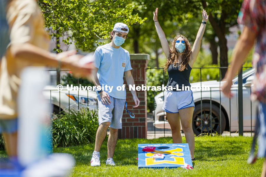 Soffi Olson celebrates her teammates throw as Kaleb Brady watches during a corn hole game at Sigma Chi recruitment day. Sigma Chi members are wearing masks as a result of the COVID-19 pandemic. May 29, 2020. Photo by Craig Chandler / University Communication.