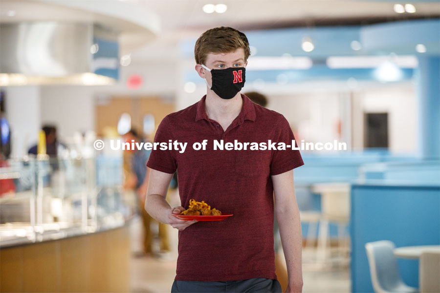 Young man wearing a Husker mask. Photo shoot of students wearing masks and practicing social distancing in dining services in Willa Cather Dining Center. July 1, 2020. Photo by Craig Chandler / University Communication.