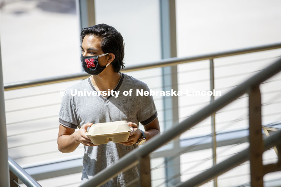 A young man wearing a Husker mask gets takeout dining from the Willa Cather Dining Center. Photo shoot of students wearing masks and practicing social distancing in dining services in Willa Cather Dining Center. July 1, 2020. Photo by Craig Chandler / University Communication.