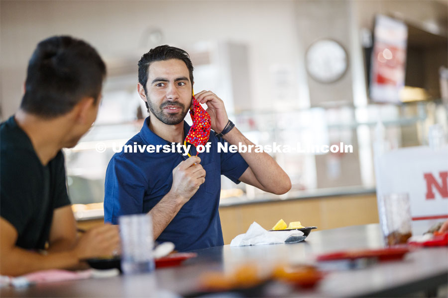 Young men having lunch together in the Willa Cather Dining Center. Photo shoot of students wearing masks and practicing social distancing in dining services in Willa Cather Dining Center. July 1, 2020. Photo by Craig Chandler / University Communication.