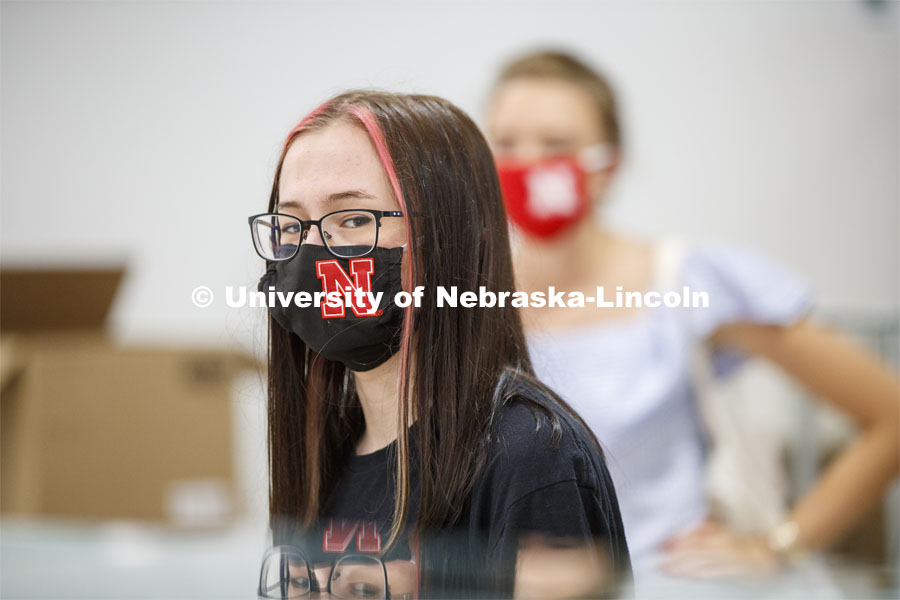 A young woman’s Husker mask matches the red stripes in her hair. Photo shoot of students wearing masks and practicing social distancing in dining services in Willa Cather Dining Center. July 1, 2020. Photo by Craig Chandler / University Communication.