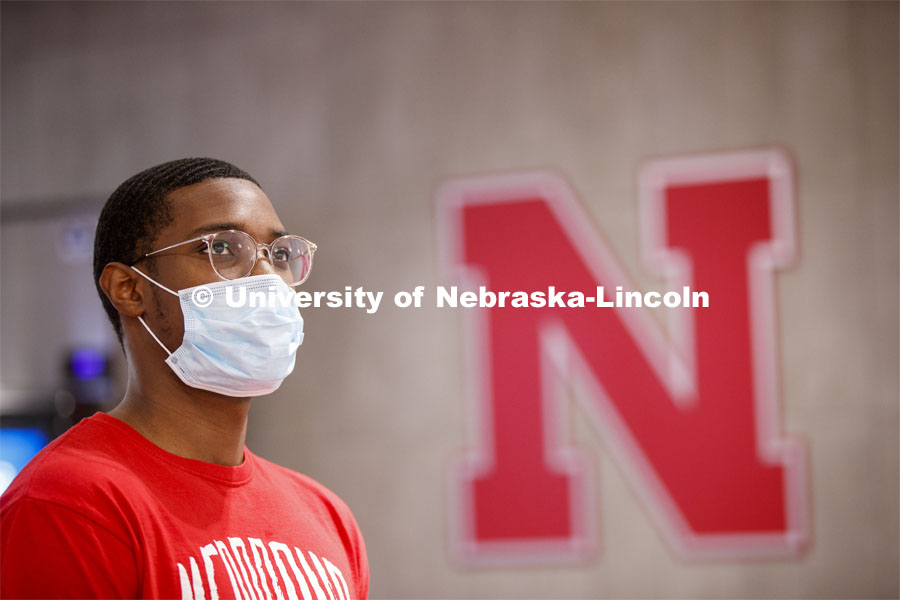 Young man wearing a mask standing next to the Nebraska N. Photo shoot of students wearing masks and practicing social distancing in dining services in Willa Cather Dining Center. July 1, 2020. Photo by Craig Chandler / University Communication.