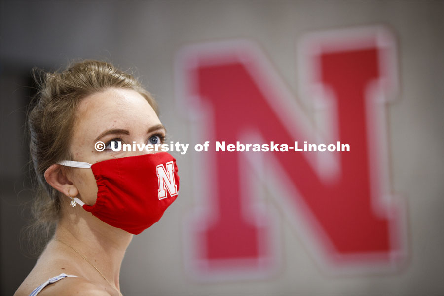 Young woman wearing a red mask stands next to the Nebraska N. Photo shoot of students wearing masks and practicing social distancing in dining services in Willa Cather Dining Center. July 1, 2020. Photo by Craig Chandler / University Communication.