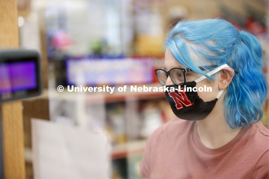 A young woman checking out in the convenience store. Photo shoot of students wearing masks and practicing social distancing in dining services in Willa Cather Dining Center. July 1, 2020. Photo by Craig Chandler / University Communication.