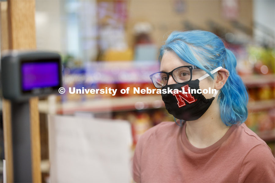 A young woman checking out in the convenience store. Photo shoot of students wearing masks and practicing social distancing in dining services in Willa Cather Dining Center. July 1, 2020. Photo by Craig Chandler / University Communication.