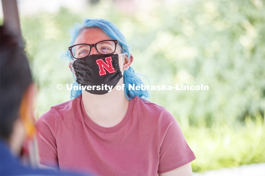 Students socialize on the patio outside the Willa Cather Dining Complex. Photo shoot of students wearing masks and practicing social distancing in dining services in Willa Cather Dining Center. July 1, 2020. Photo by Craig Chandler / University Communication.