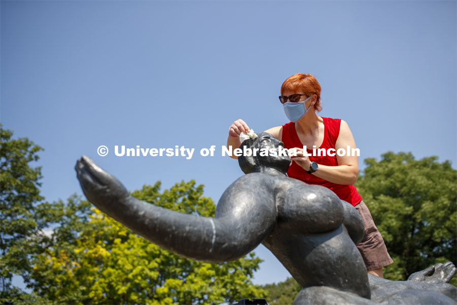 Stacey Walsh, the Sheldon Museum of Associate Registrar for Collections and Exhibitions, rids Floating Figure, a sculpture by Gaston Lachaise, of avian art critic reviews. Walsh was getting the sculpture ready for a photo shoot featuring UNL campus sculptures wearing masks. Mask wearing statues on campus. July 6, 2020. Photo by Craig Chandler / University Communication.