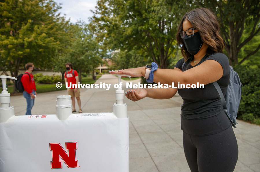 Photo shoot of students on city campus practicing hand sanitizing. A young woman stops at a hand sanitizing station to clean her hands. August 5, 2020. Photo by Craig Chandler / University Communication.