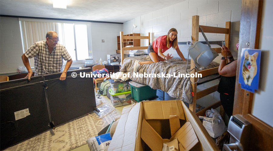 Kailey Trampe of Axtell, NE, smiles for her mom, Sara, as she makes her bed. Kailey's dad, Todd, works on assembling the futon. First day of residence hall move in. August 13, 2020. Photo by Craig Chandler / University Communication.