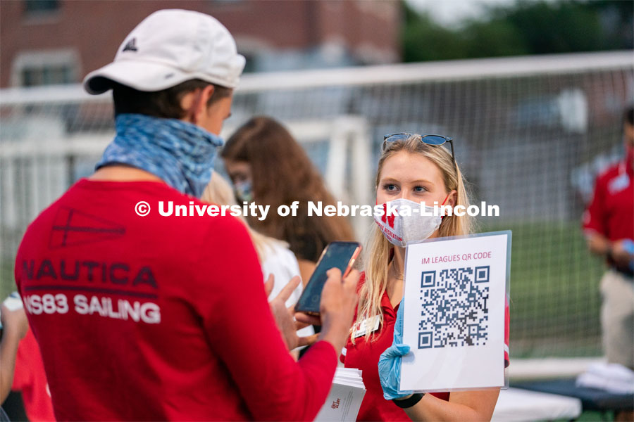 A Nebraska Campus Recreation employee (right) holds up a QR code for students to scan during the HuskerMania Masker Singer event at Mabel Lee Fields. August 21, 2020. Photo by Jordan Opp for University Communication.
