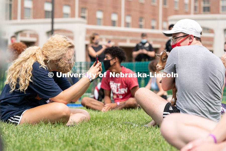 Freshman Meredith Game (left) takes a photo of Freshman Ian Mitchell (right) holding a goat during Wellness Fest at Meier Commons. August 22, 2020. Photo by Jordan Opp for University Communication.