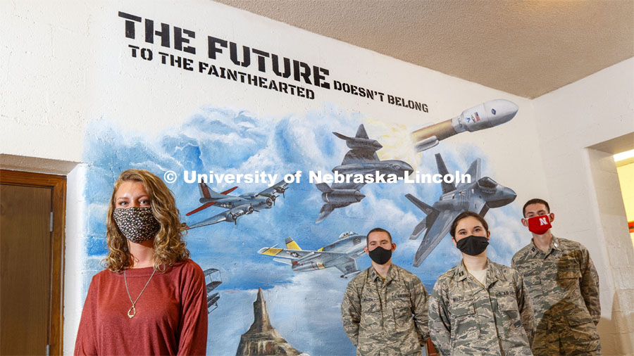 Artist, Anna Binder poses along with Cadet Major Lucas Heaton, Cadet 2nd Lt. Isabel Welch and Cadet 2nd Lt. Anthony Massaro in front of the mural that Binder painted for the AFROTC hallway to honor Cadet Alex Kearns. August 31, 2020. Photo by Craig Chandler / University Communication.